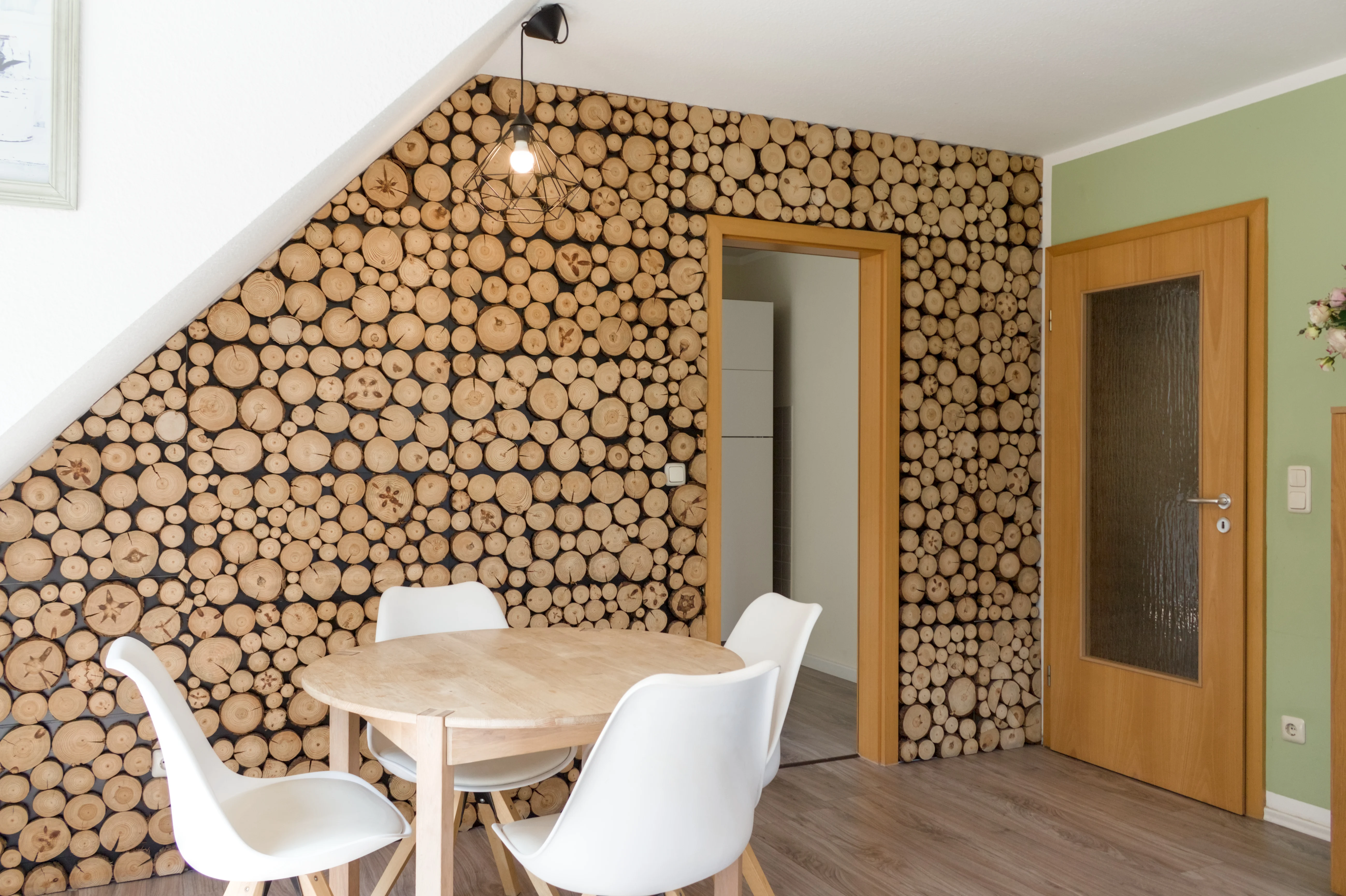 Essbereich vor einer Akzentwand aus Holzscheiben